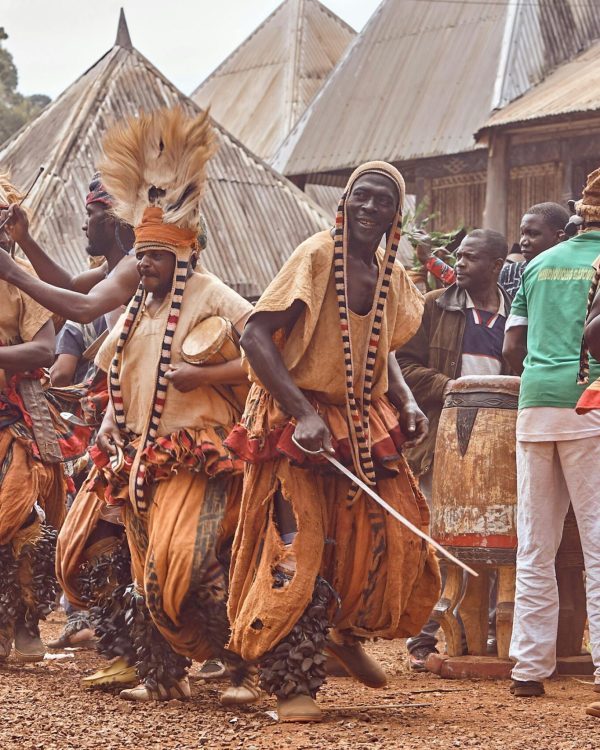 Traditional African dancers performing in colorful outfits during a cultural festival outdoors.