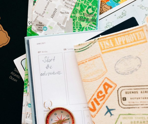Flat lay of travel essentials including compass, notebook, and map for a journey.