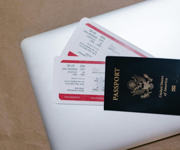 Close-up of a passport and boarding passes on a laptop, symbolizing travel preparation.
